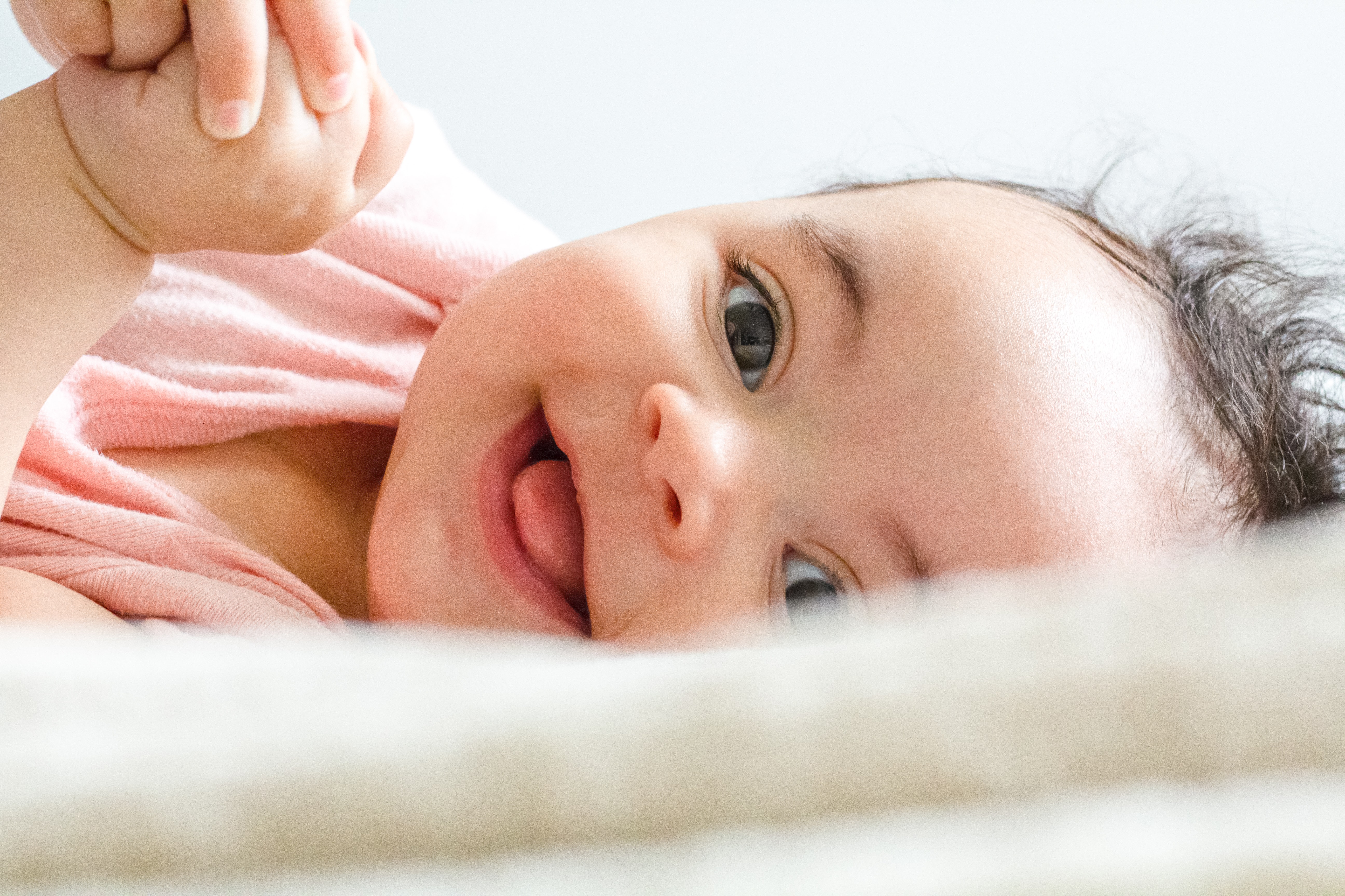 Babyfotografie - baby lächelt mit blauen augen in die kamera